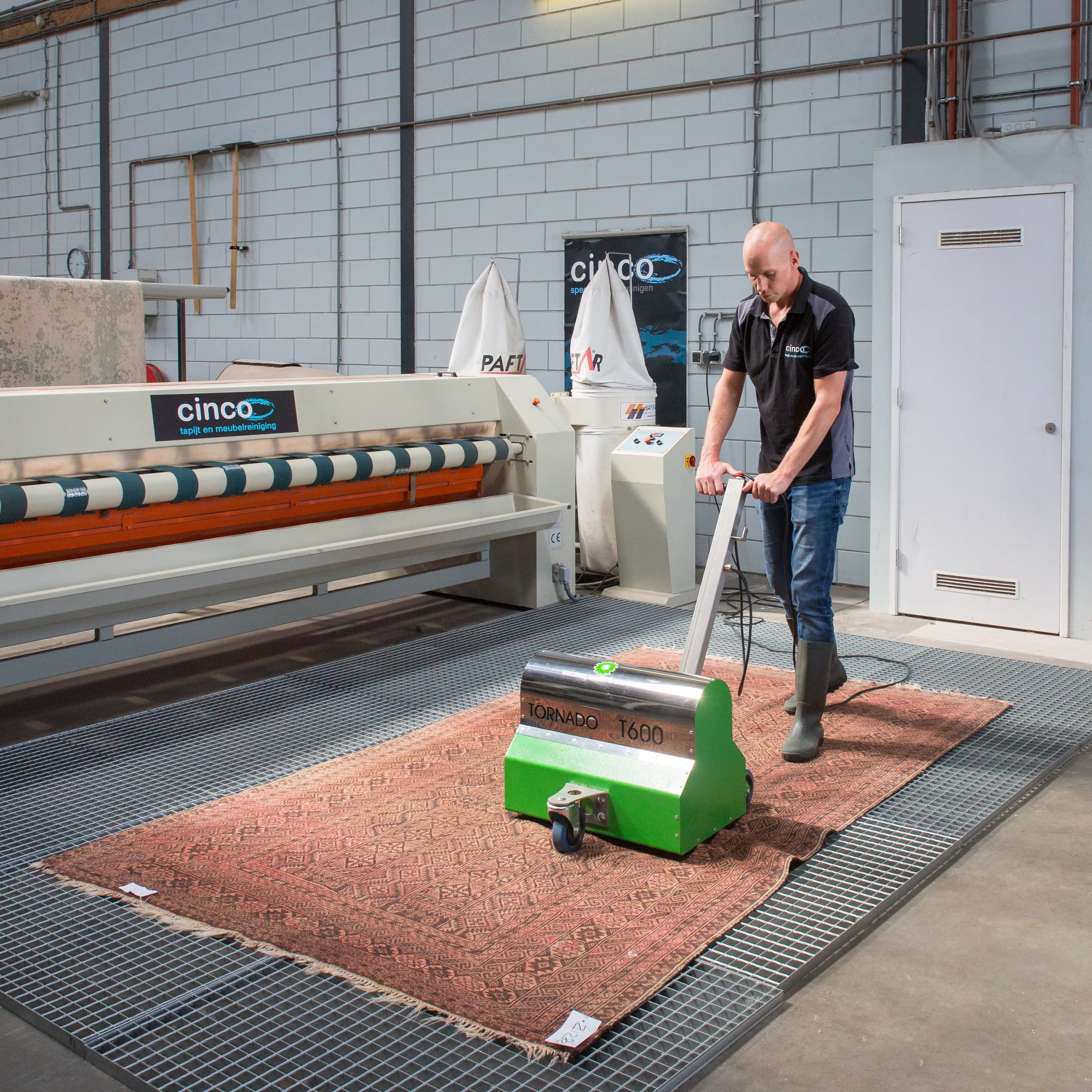 Medewerker behandelt Perzisch vloerkleed met reinigingsmachine in professionele tapijtwasserij